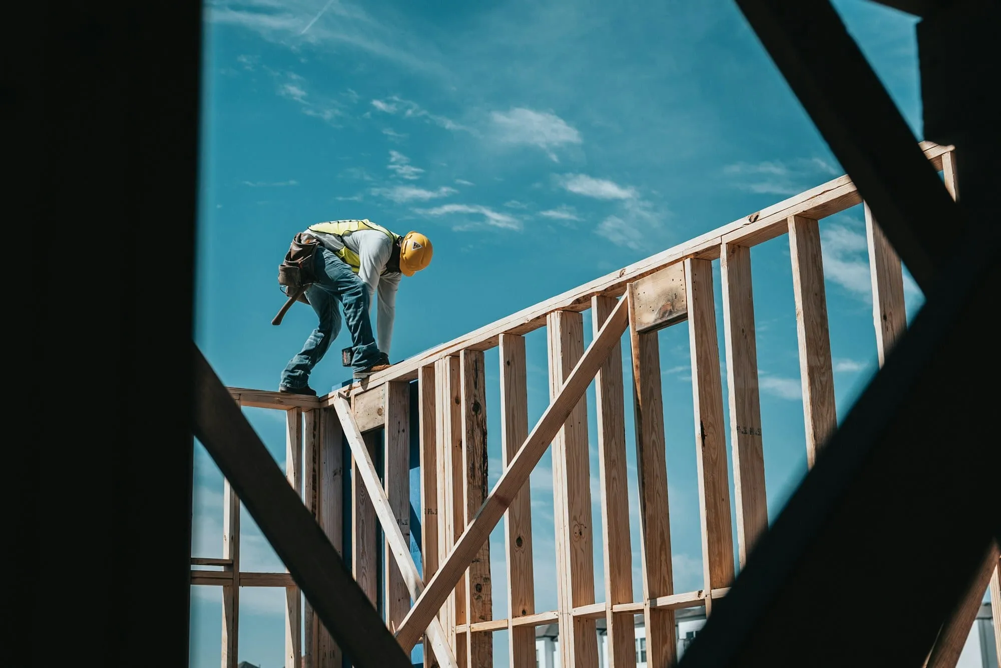 Builder working on a timber frame against a blue sky
