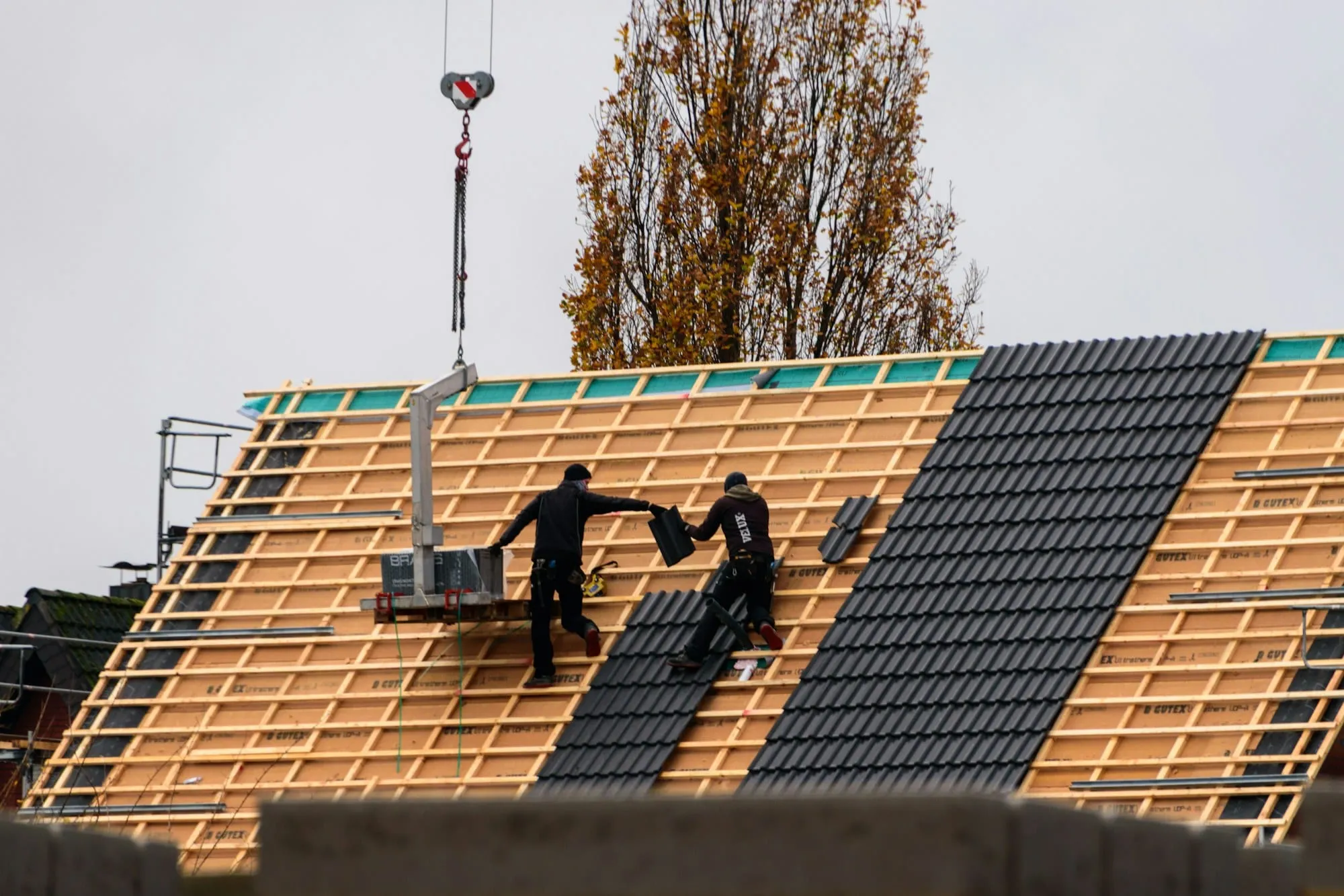 Roofers fitting new tiles on fresh battens