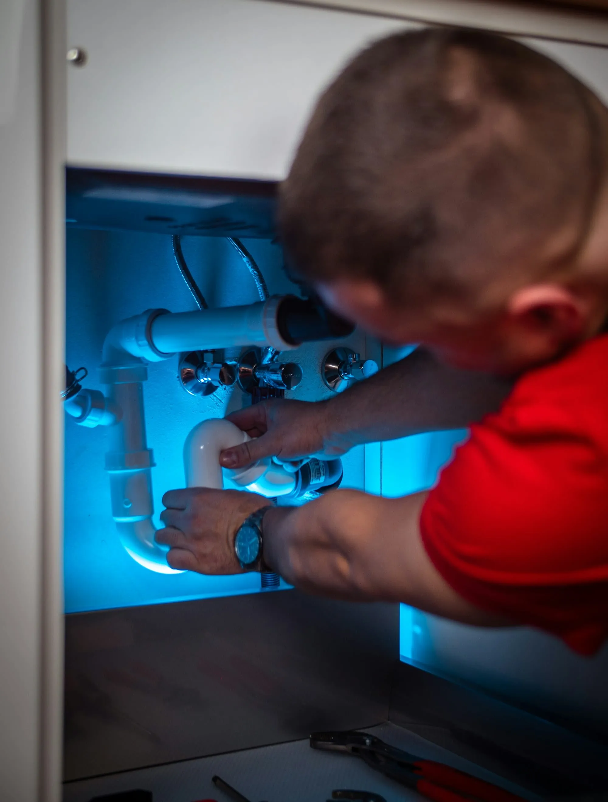 Plumber fixing pipes under a sink