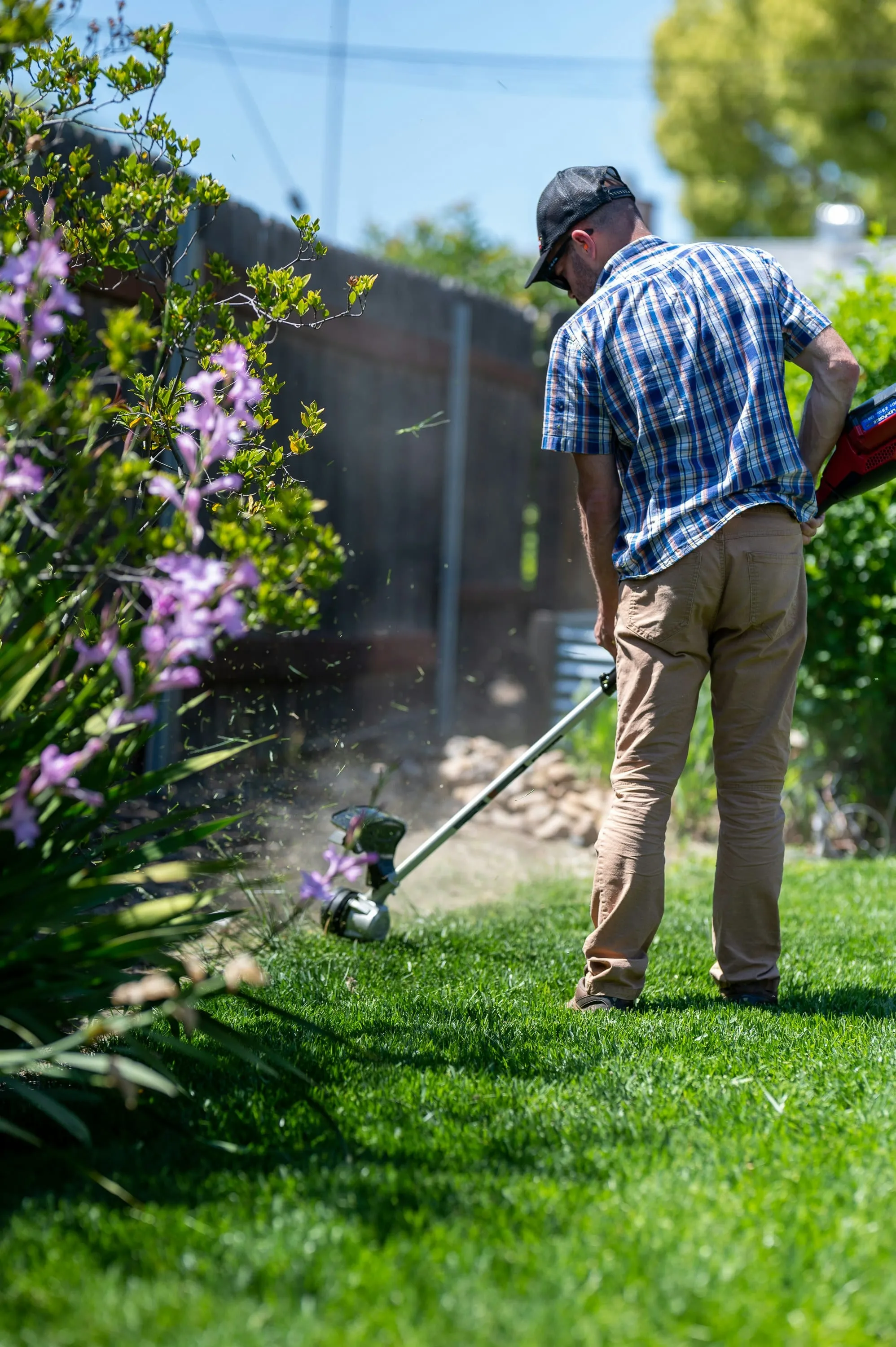 Landscaper trimming lawn edges with a string trimmer