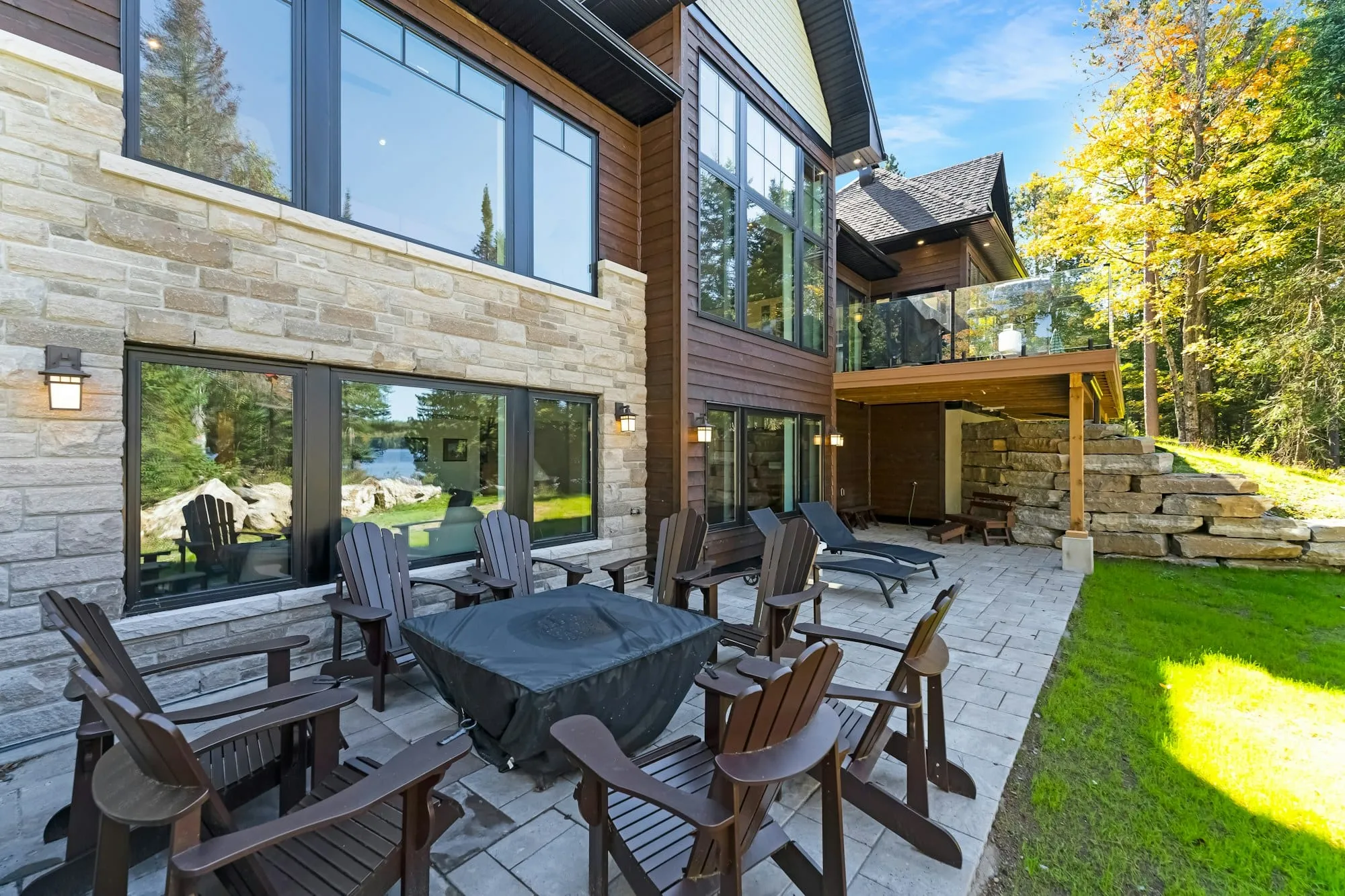 Stone patio with wooden chairs behind a modern house